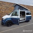 Passenger side profile of the Bamboo Green and Candy White Spartan campervan highlighting the sliding door, side bars and sleek camper conversion styling.