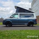Passenger side profile of the Bamboo Green and Candy White Spartan campervan highlighting the sliding door, side bars and sleek camper conversion styling.