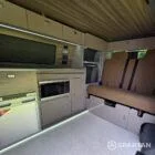 Interior view of a VW SWB Spartan campervan with Winter flooring, Mocca and Driftwood cabinetry, Liquor upholstery, passenger double bench seat and rock and roll bed.