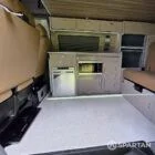 Side view of the camper conversion highlighting the kitchen, wardrobe, rock and roll bed and Winter floor throughout.