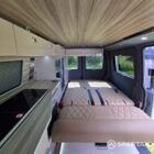 Full interior view from the rear doors showing the rock and roll bed, wardrobe and kitchen layout.